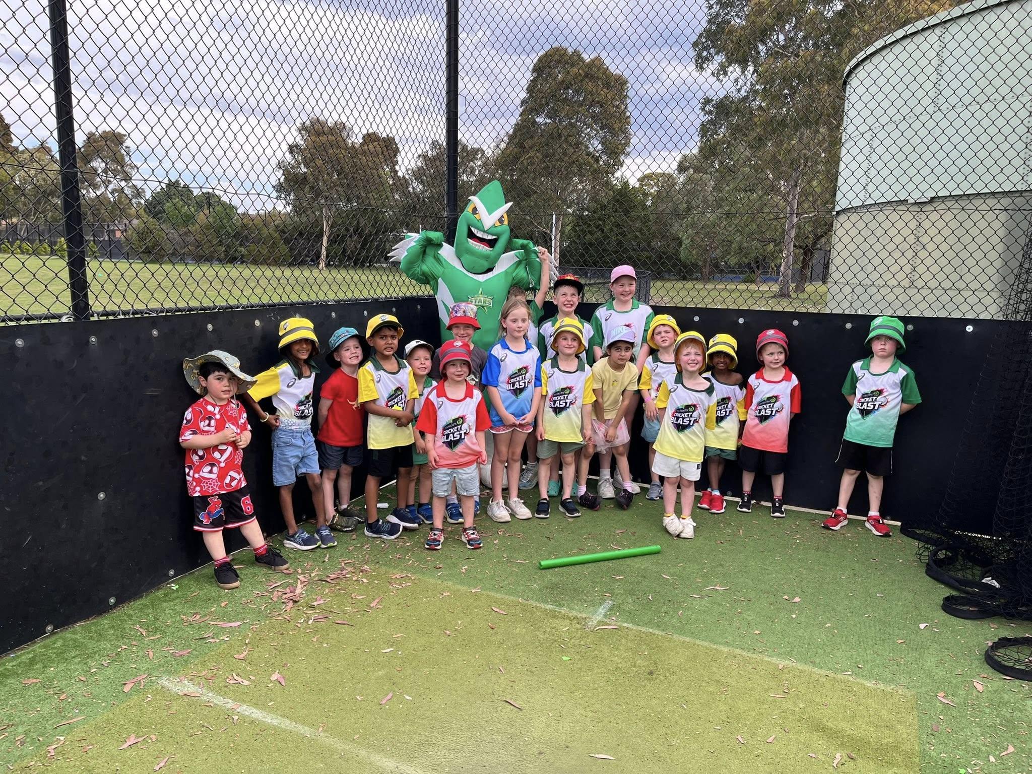 A group of Cricket Blast kids in their Cricket Blast shirts, posing with a Big Bash club mascot at Eildon Park